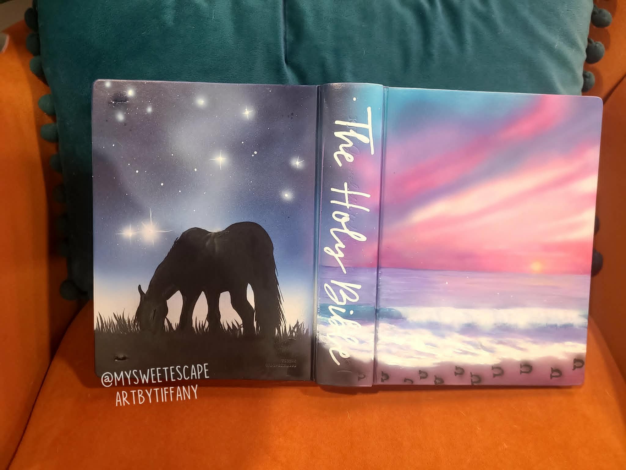 Hand-painted Bible cover with airbrushed grazing horse silhouette under a starry night sky on one side and a pink and purple ocean sunset on the other