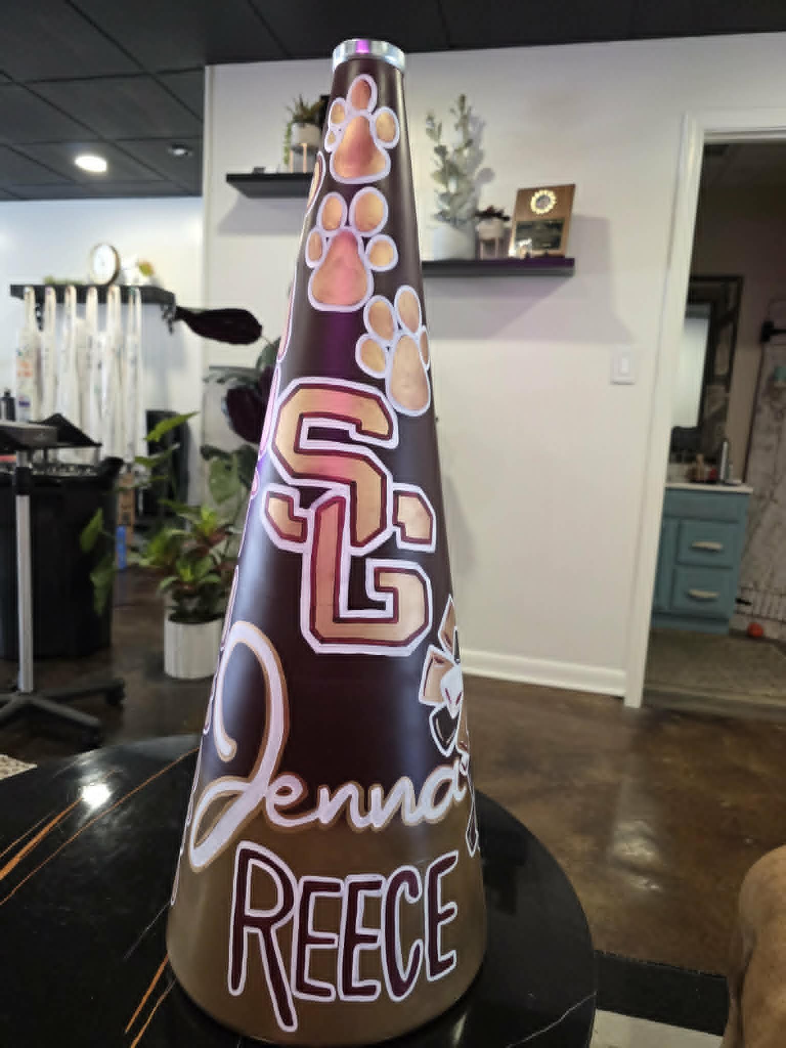 Hand-painted Spring Garden cheerleading megaphone for Jenna Reece in maroon and gold with paw prints, the SG team logo, and a megaphone-and-bow accent