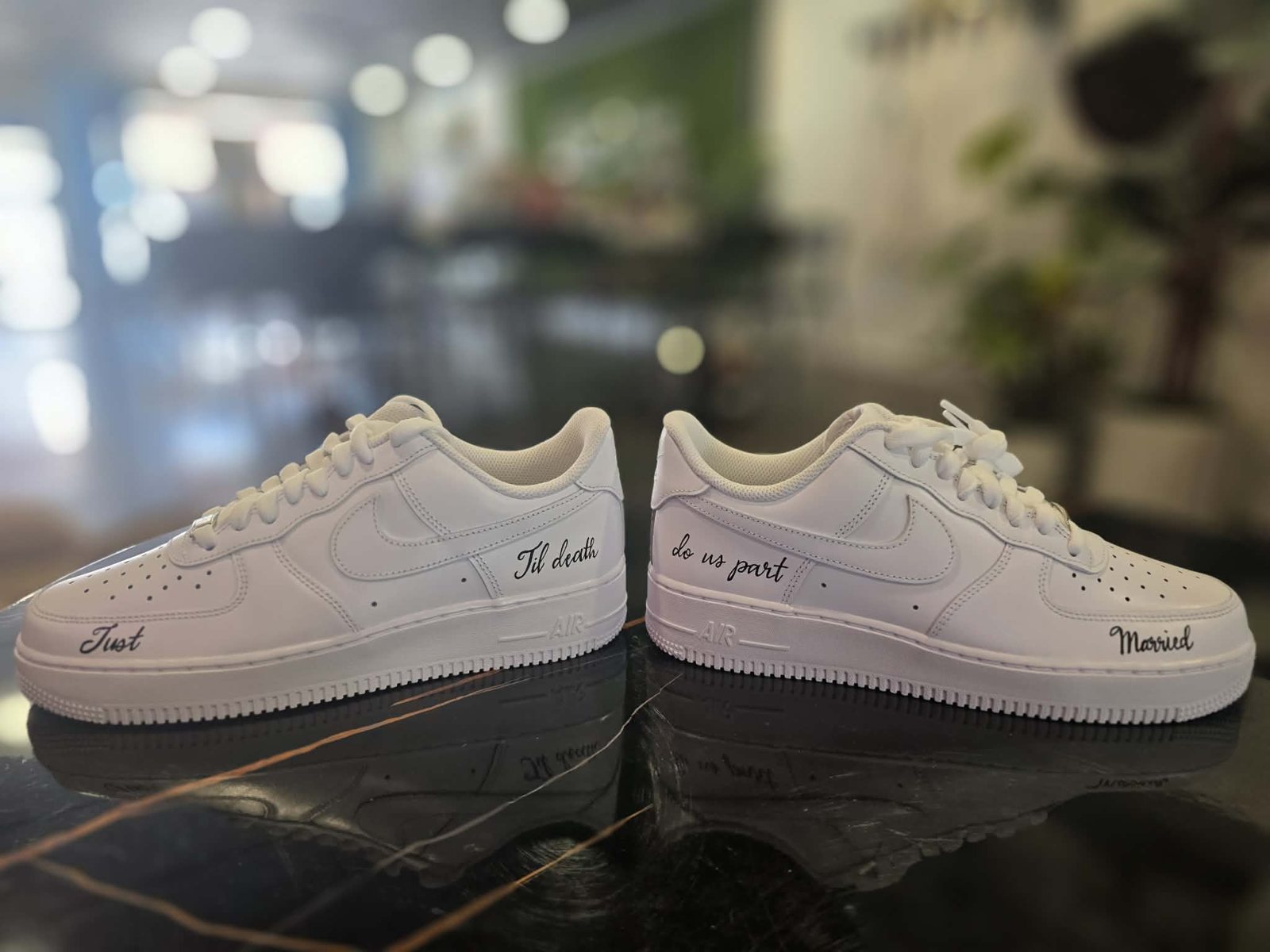 Hand-lettered white Nike Air Force 1 wedding sneakers with 'Just Married' across the toes and 'Til death do us part' in black script along the sides