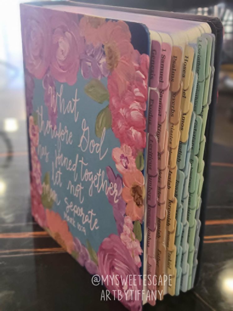 Hand-painted Bible standing upright showing floral cover and pastel book tabs