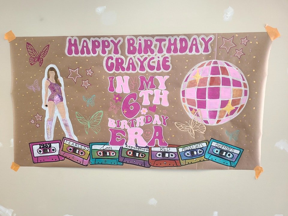 Hand-painted Taylor Swift Eras-themed 6th birthday banner reading 'Happy Birthday Graycie, In My 6th Birthday Era' with disco ball, butterflies, and album cassettes