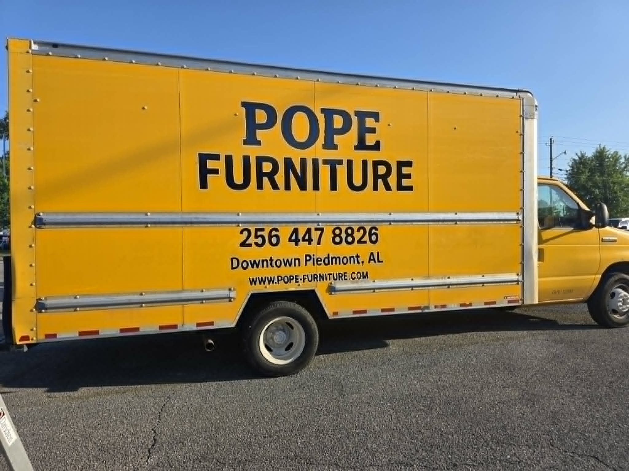 Side view of a yellow Pope Furniture box truck with bold black hand-painted lettering and Downtown Piedmont, AL details