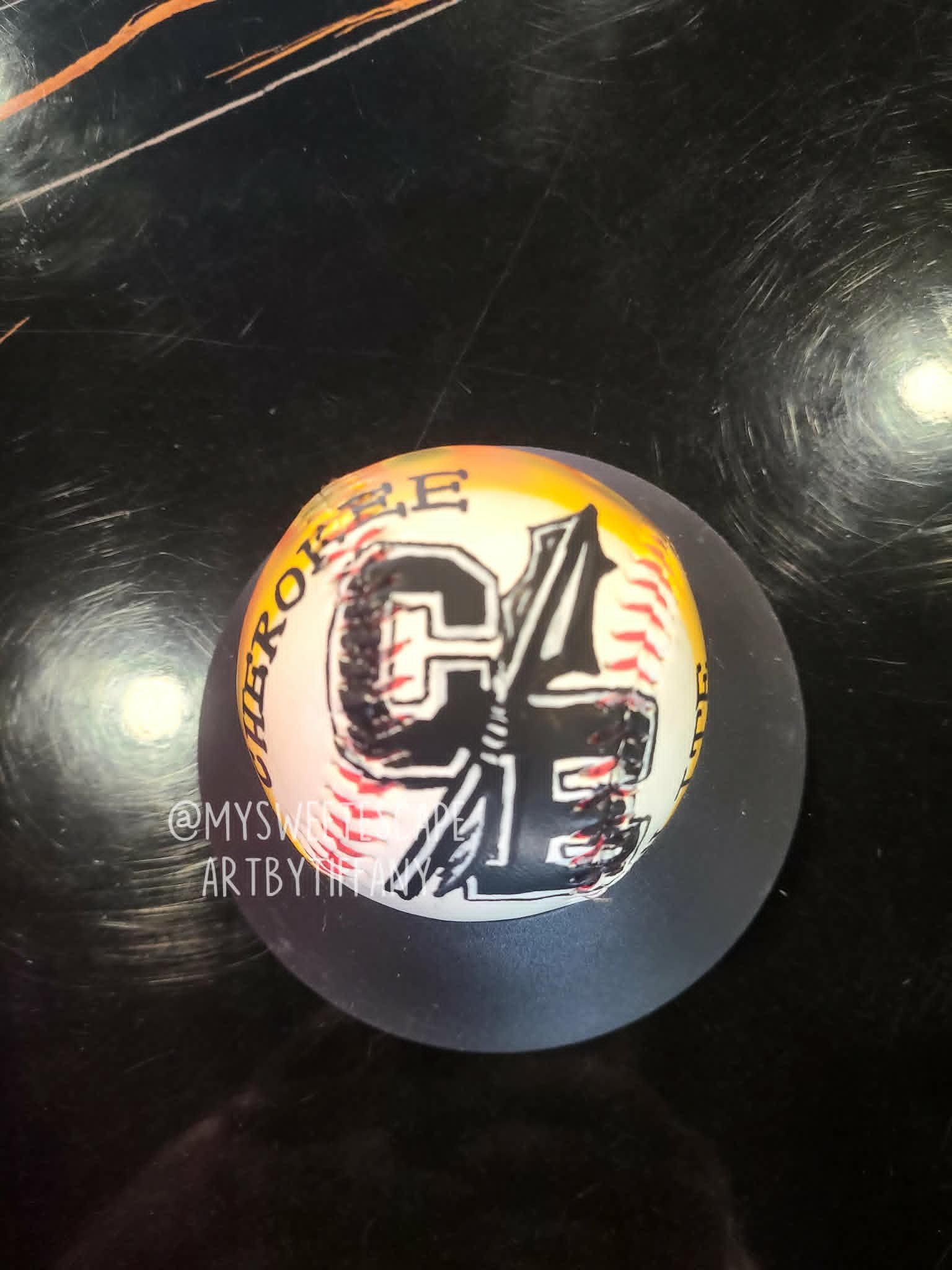 Airbrushed baseball with Cherokee Cardinals 'CC' varsity logo, tomahawk feather, and yellow flame border