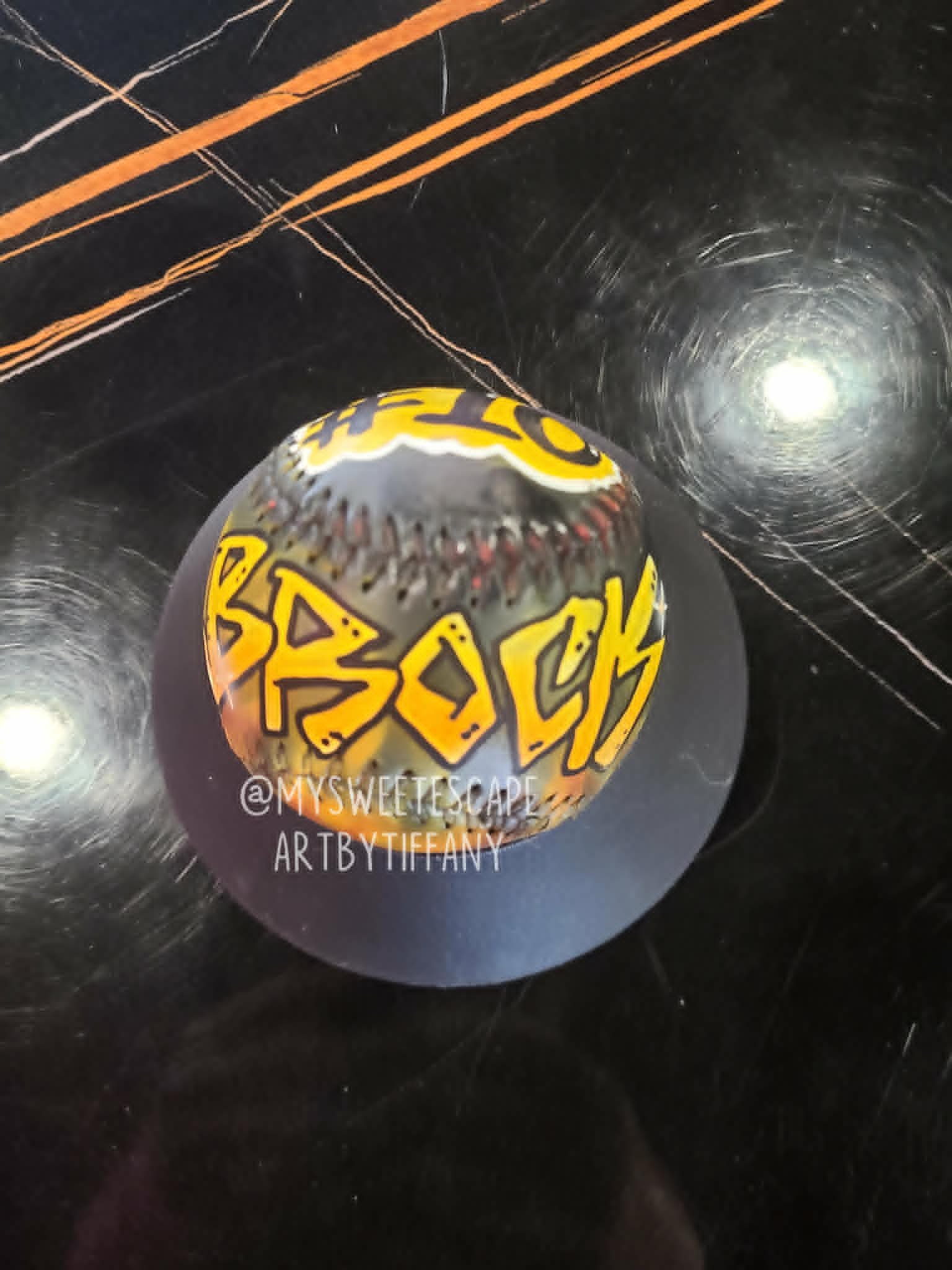 Airbrushed yellow and black softball with 'Brock' in bold yellow graffiti lettering