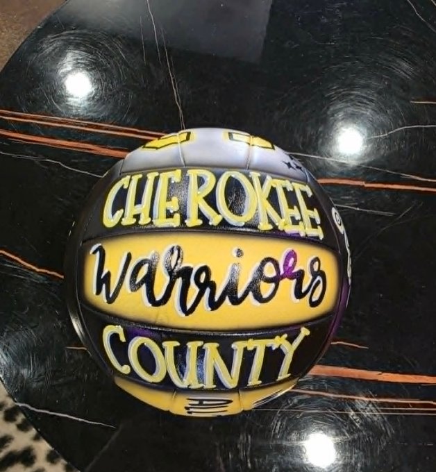 Hand-painted purple and yellow Cherokee County Warriors volleyball with bold script and block lettering