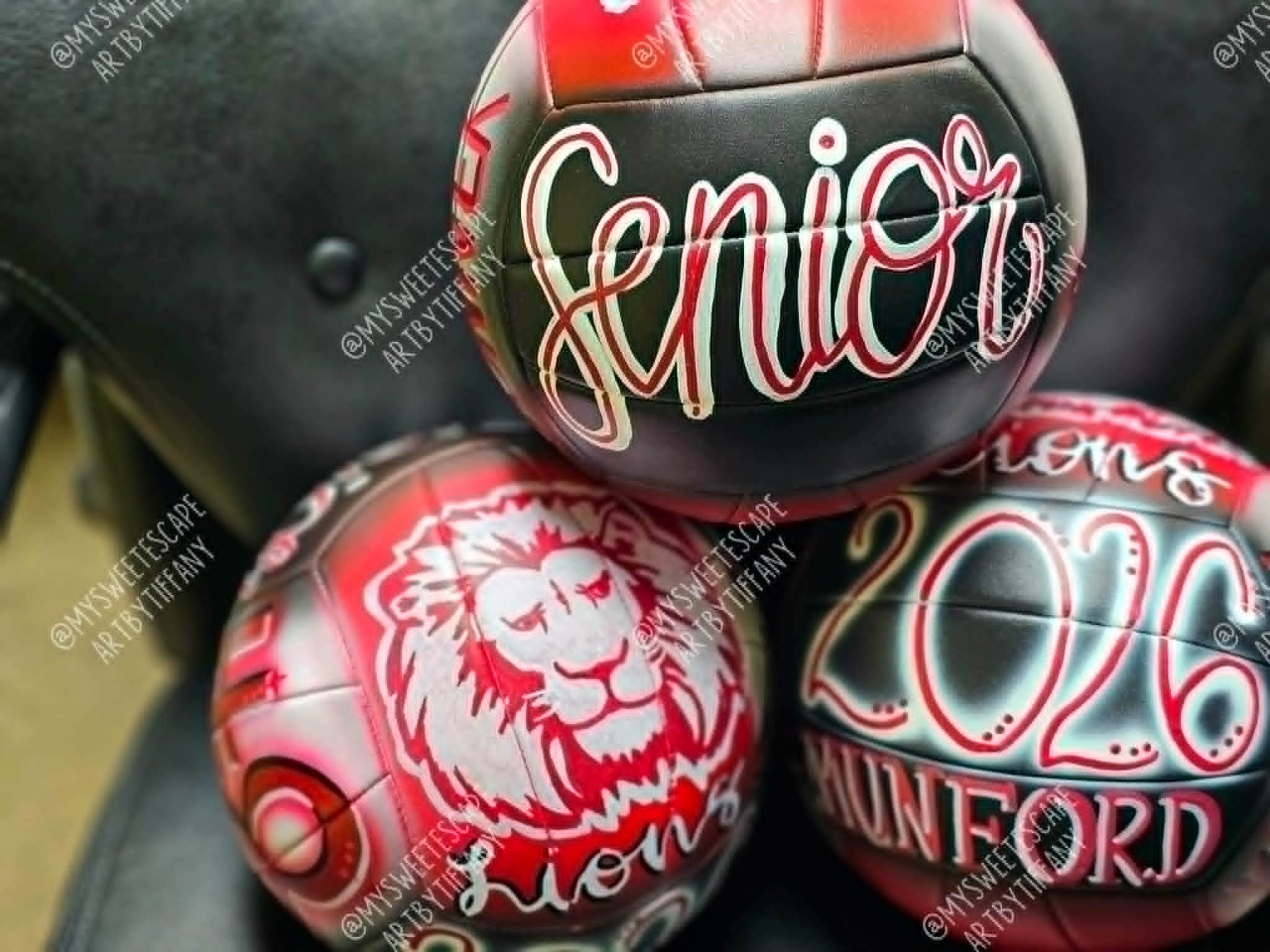 Set of three hand-painted Munford Lions senior volleyballs in red, black, and white with lion mascot, 'Senior' script, and Class of 2026