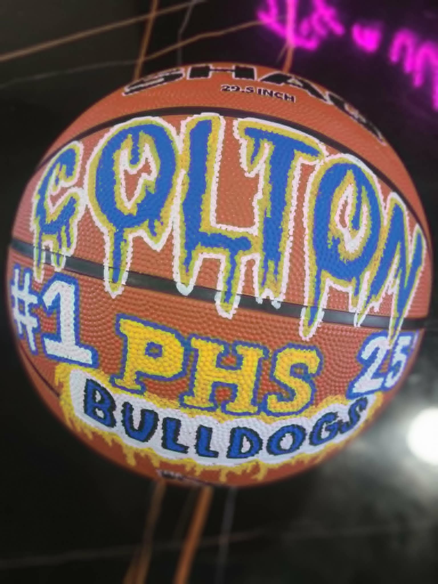 Hand-painted basketball with 'Colton' dripping graffiti lettering, '#1 PHS Bulldogs 25' detail in blue, yellow, and white