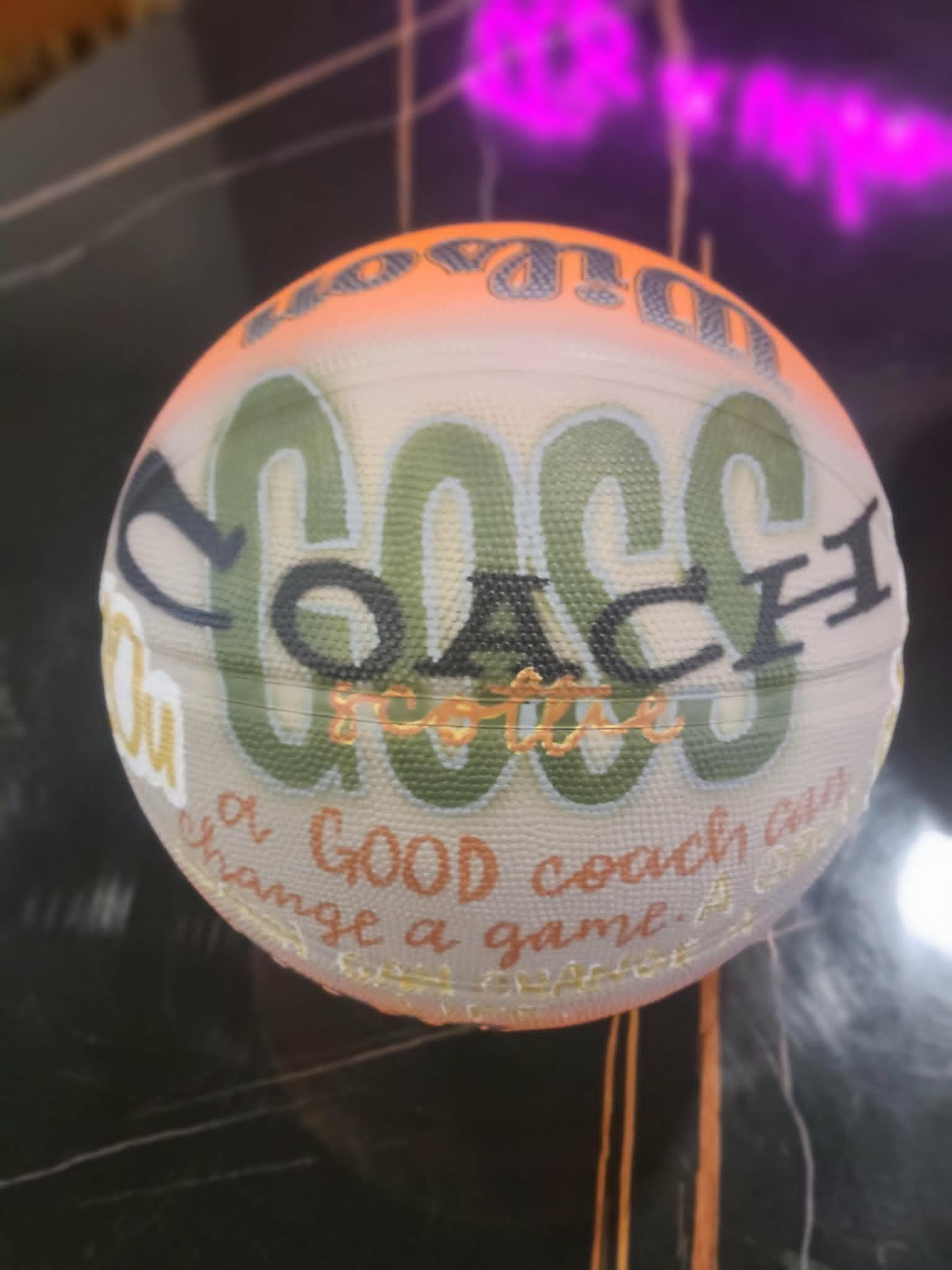 Hand-painted coach's basketball for Coach Scottie in green, gold, and orange with 'A good coach can change a game' inspirational quote