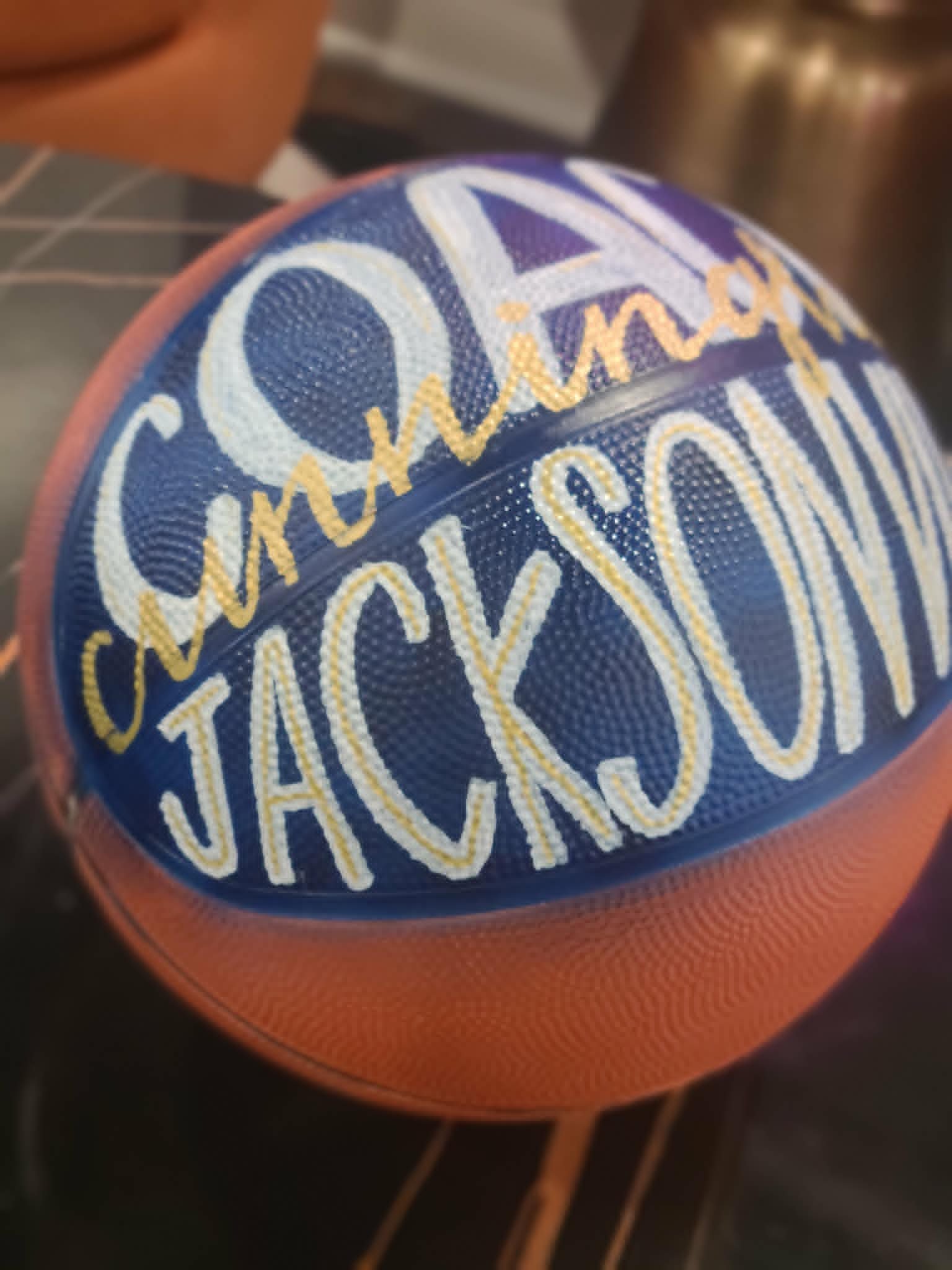 Hand-painted basketball for Cunningham Jackson with bold blue, white, and gold graffiti lettering