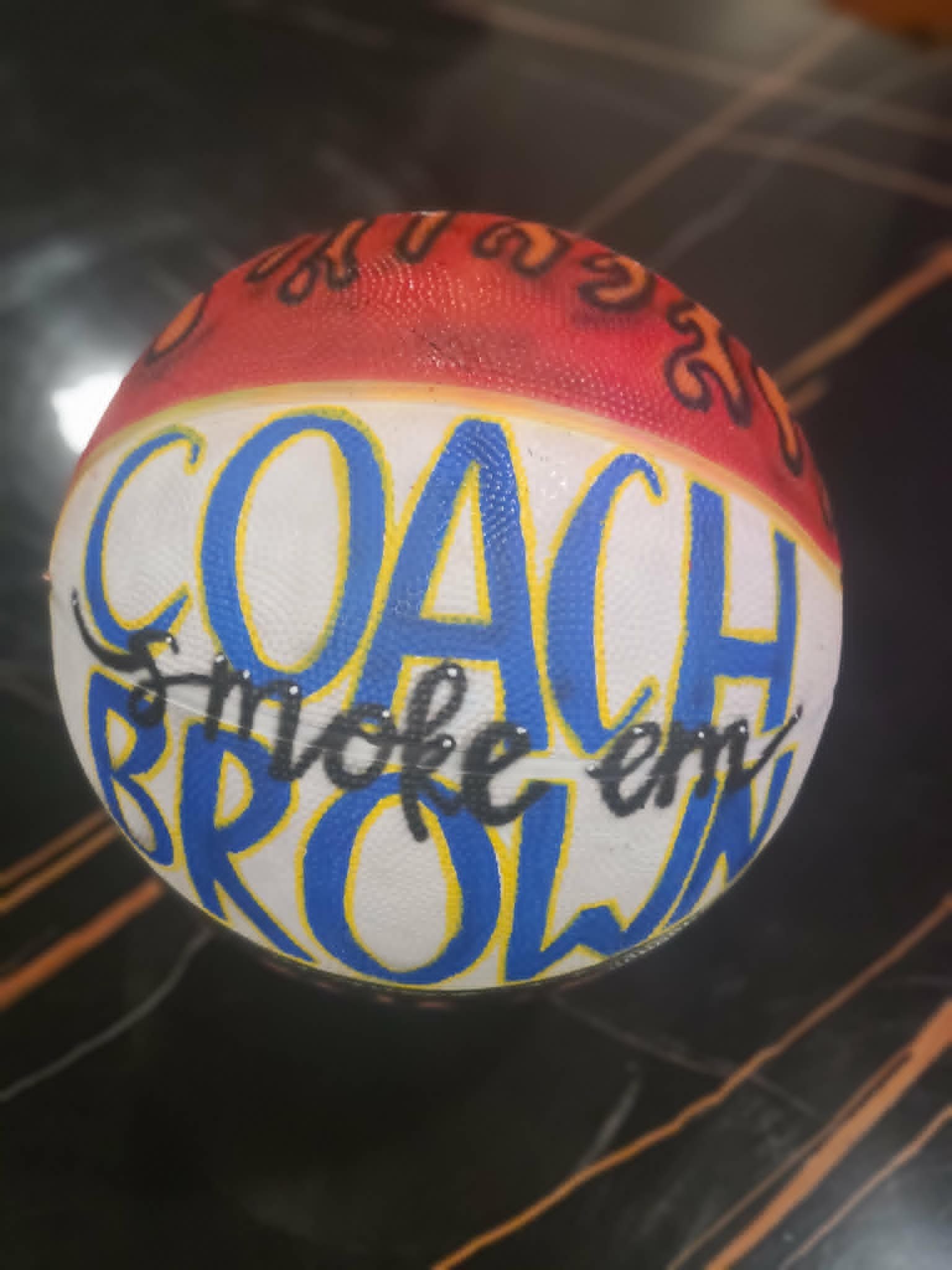 Hand-painted Coach Brown basketball with red flames, blue and yellow lettering, and 'Smoke 'em' script tagline