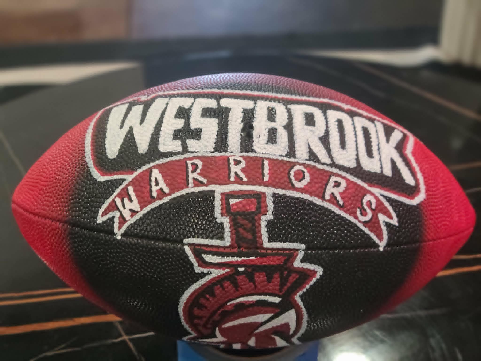 Hand-painted Westbrook Warriors football in red and black with banner-style lettering and warrior helmet logo