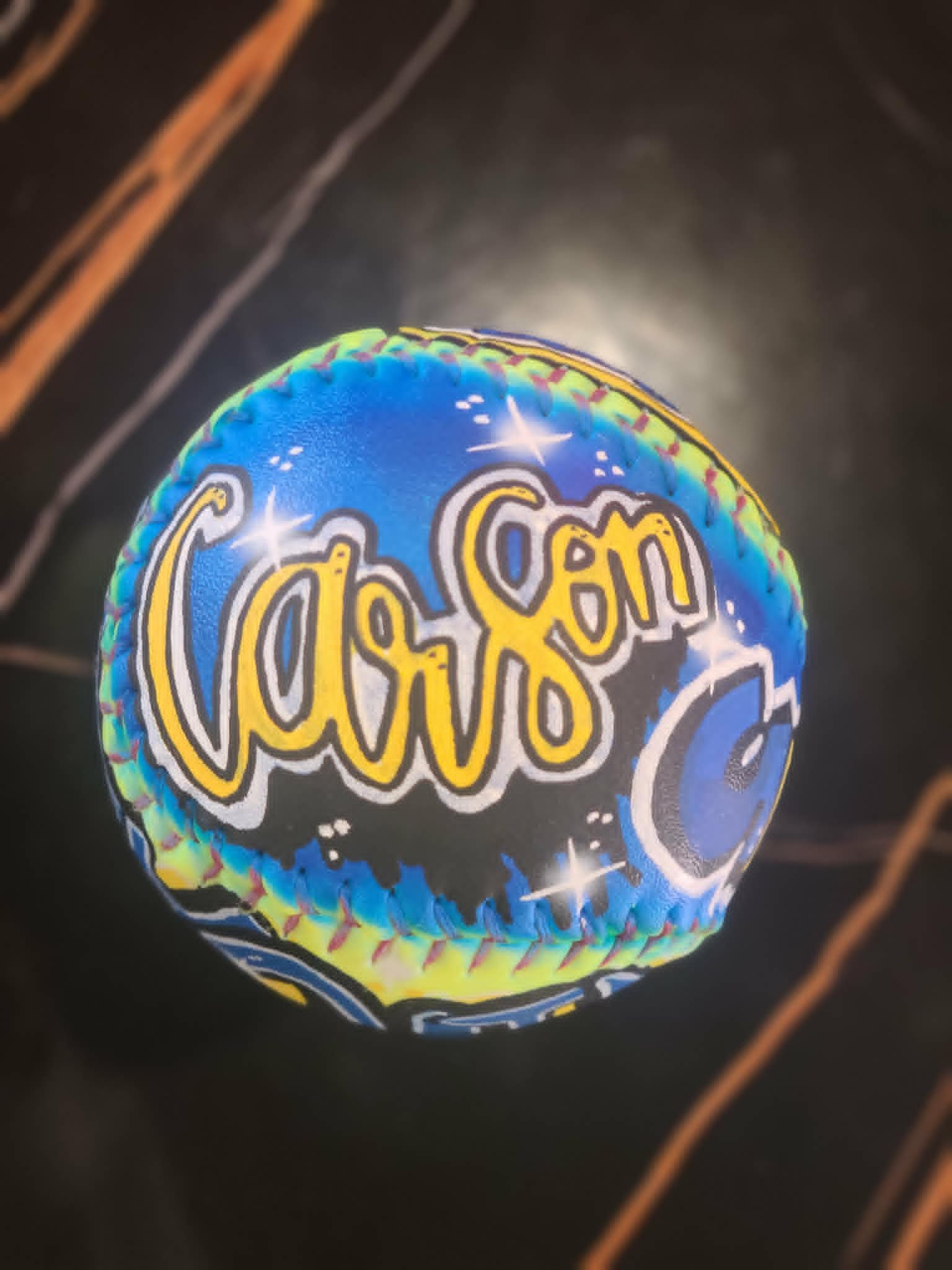 Airbrushed baseball with 'Carson' in yellow script over starry blue night-sky background and crescent moon detail
