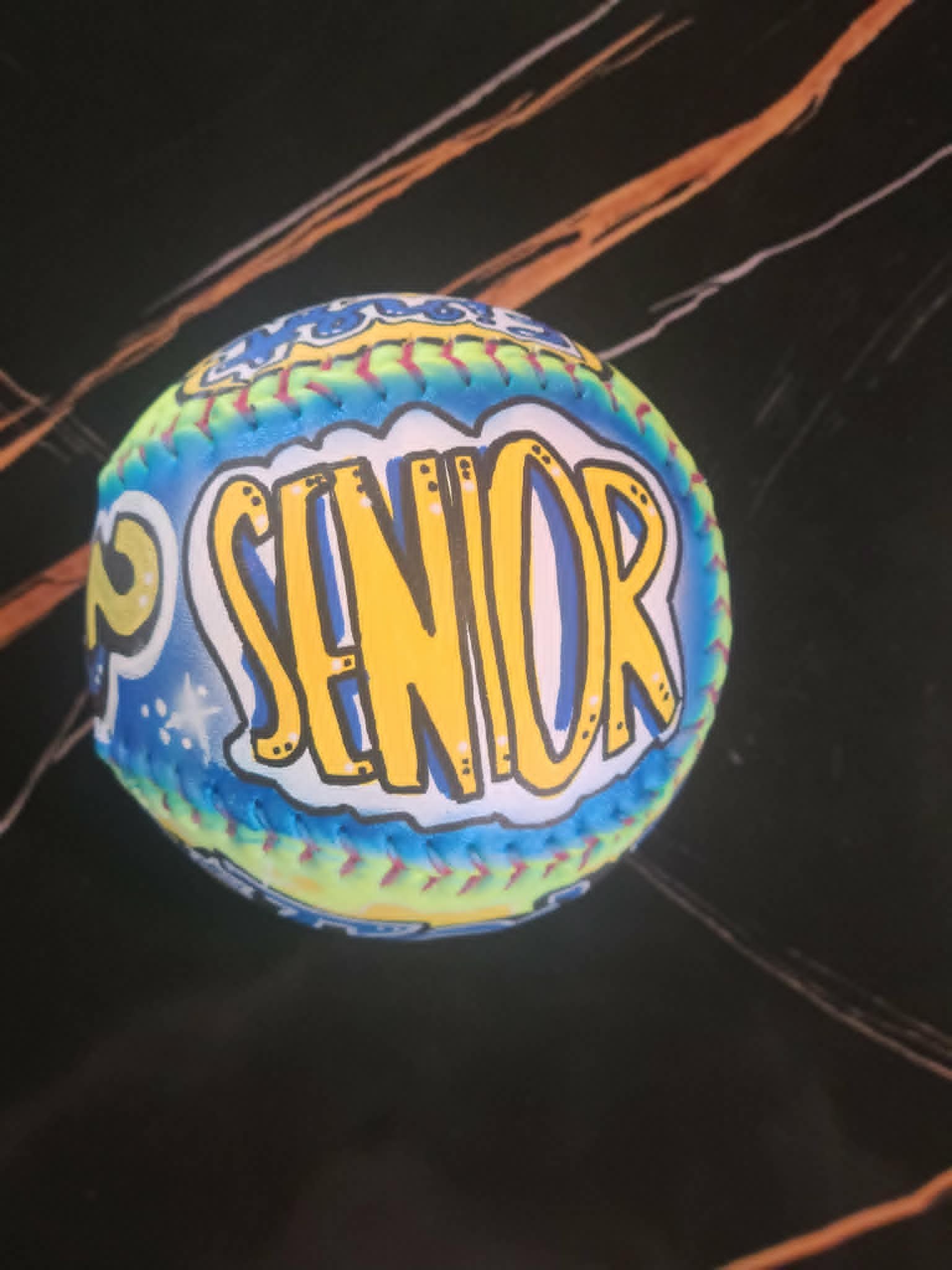 Airbrushed baseball with bold yellow 'Senior' bubble lettering on blue and green starry background