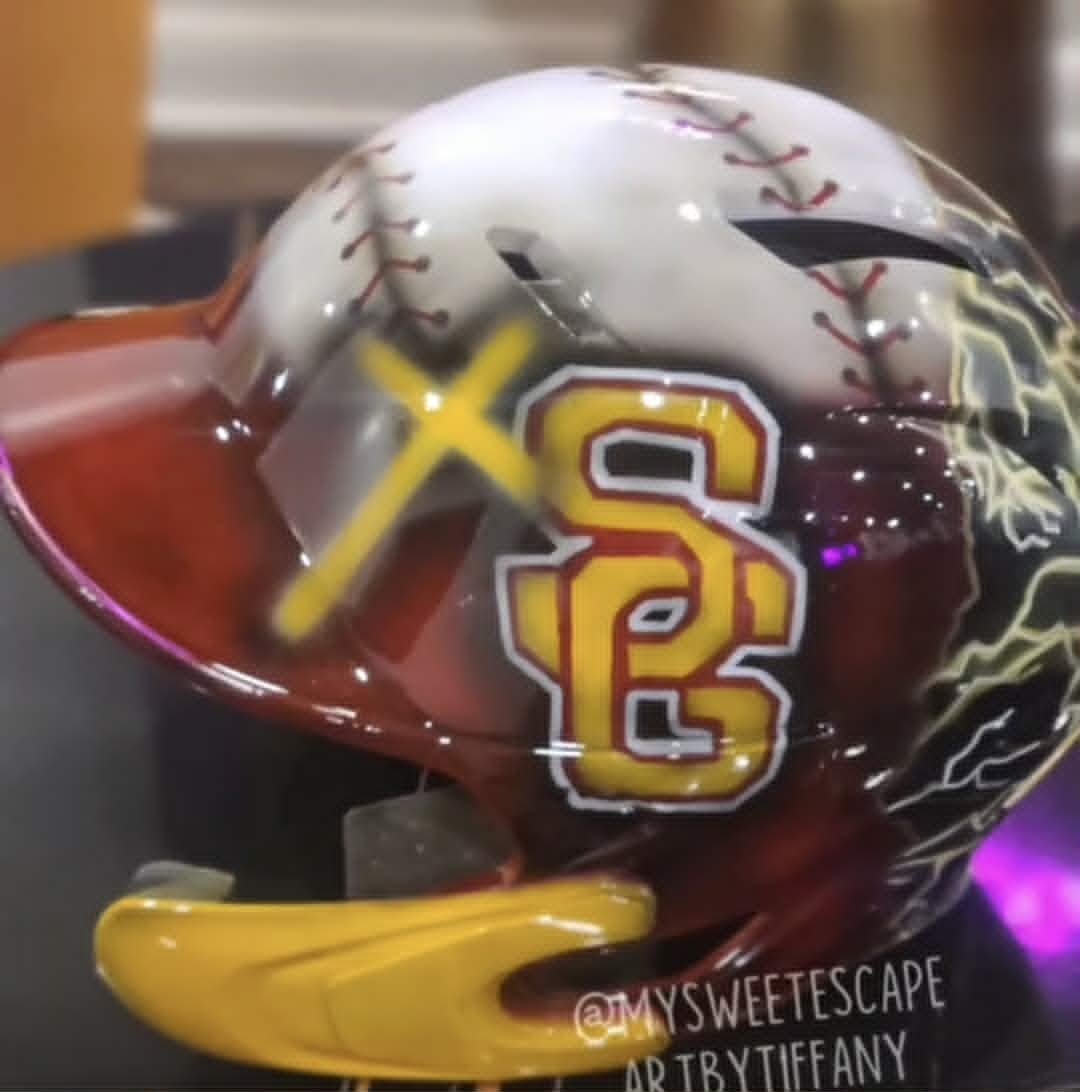 Custom airbrushed Spring Garden batting helmet painted as a baseball with red and yellow 'SG' varsity logo and lightning bolt accents