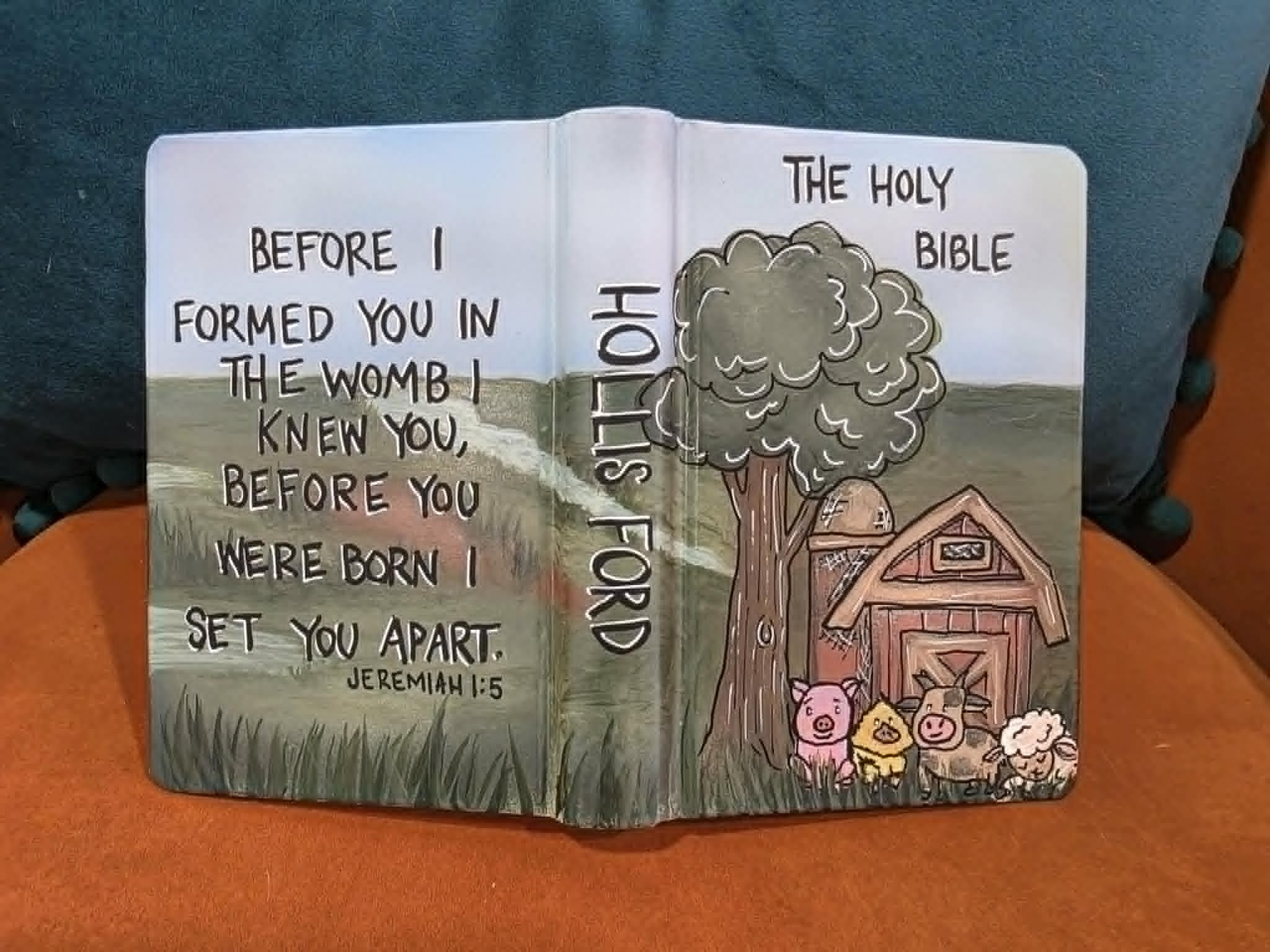 Hand-painted Bible cover for Hollis Ford with cartoon farm scene featuring a barn, tree, pig, chick, cow, and sheep, with Jeremiah 1:5 verse