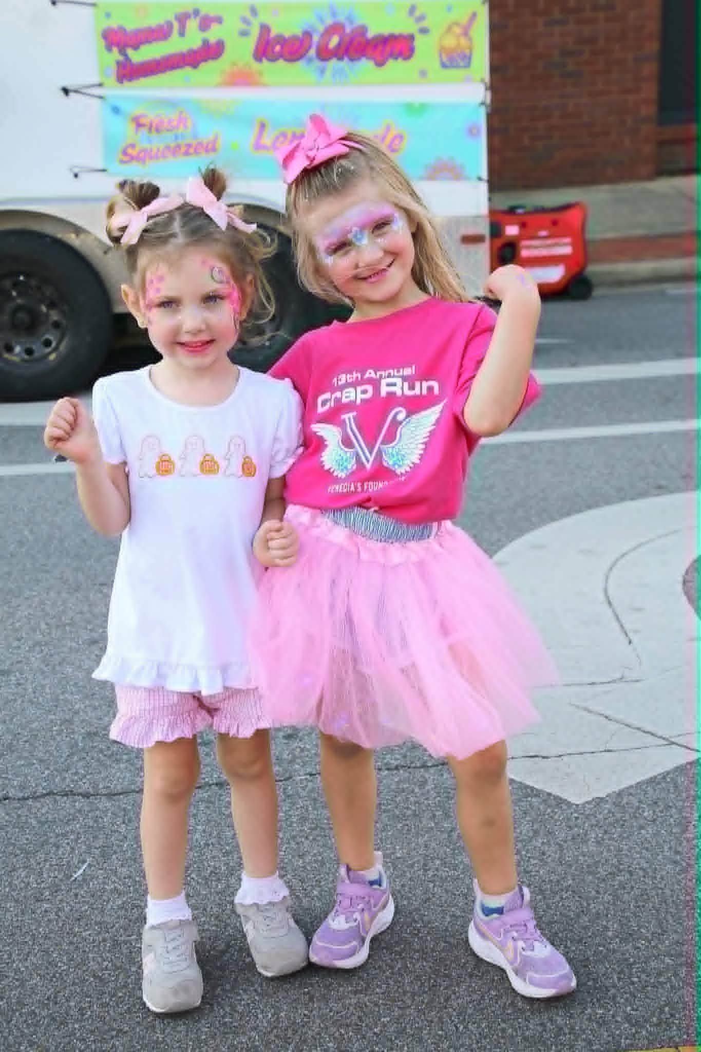 Tiffany carefully applying delicate blue and pink unicorn eye face paint to a young girl at a downtown event