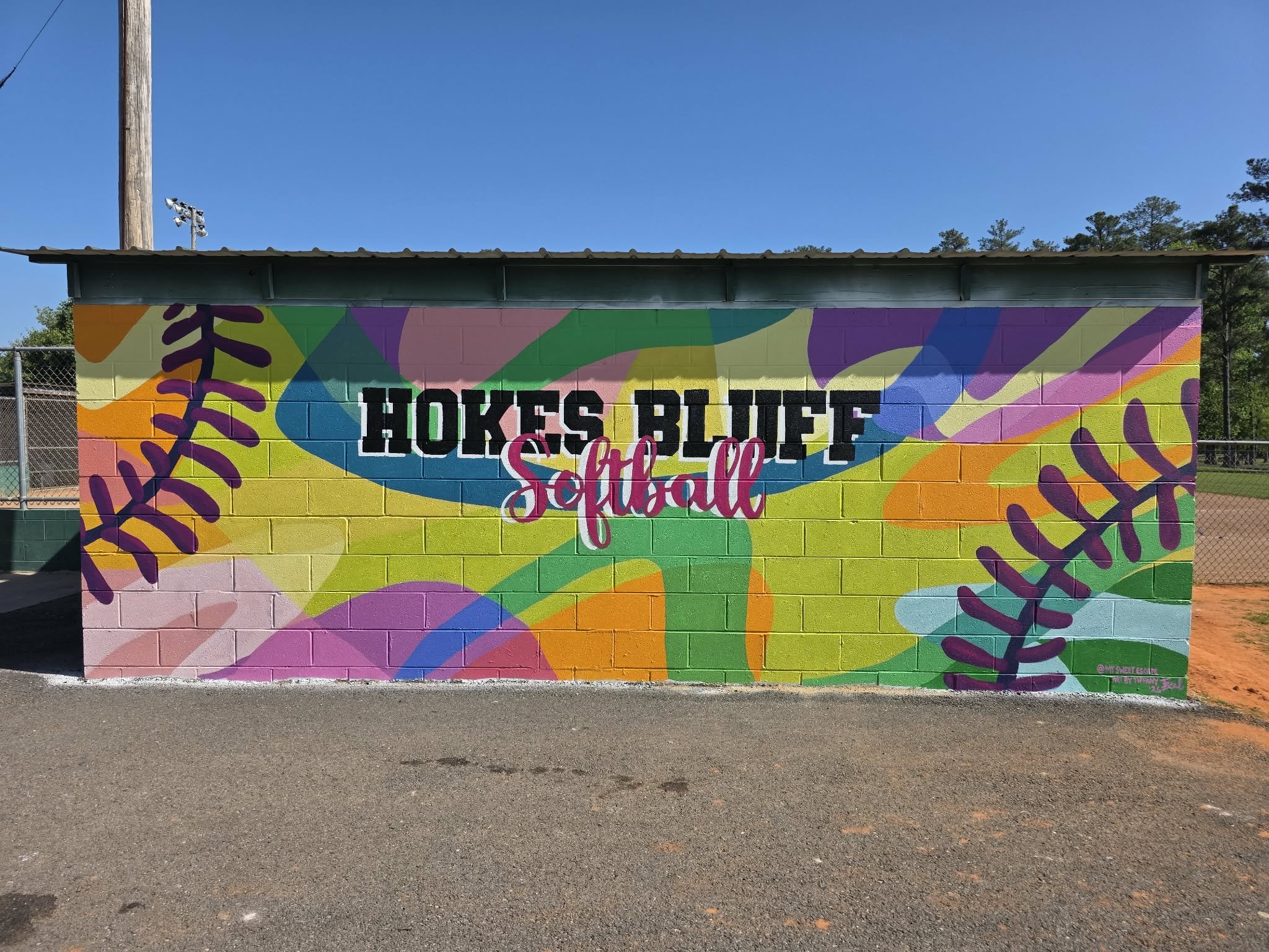 Hokes Bluff Softball dugout mural with bold colorful abstract shapes and giant softball stitching wrapping around the sides