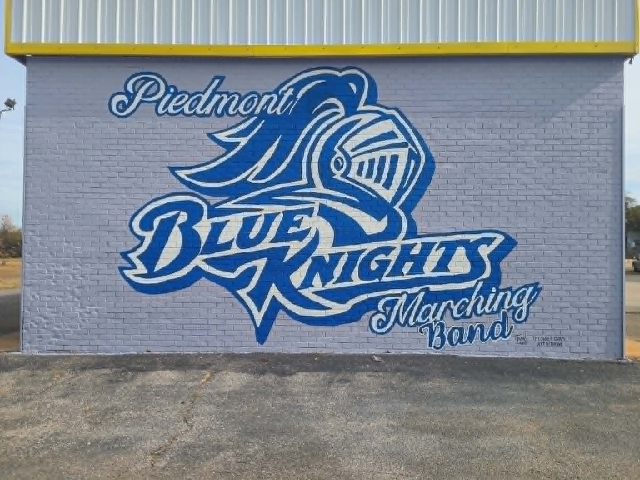 Piedmont Blue Knights Marching Band exterior mural with a bold blue knight head logo and flowing script lettering on a brick wall