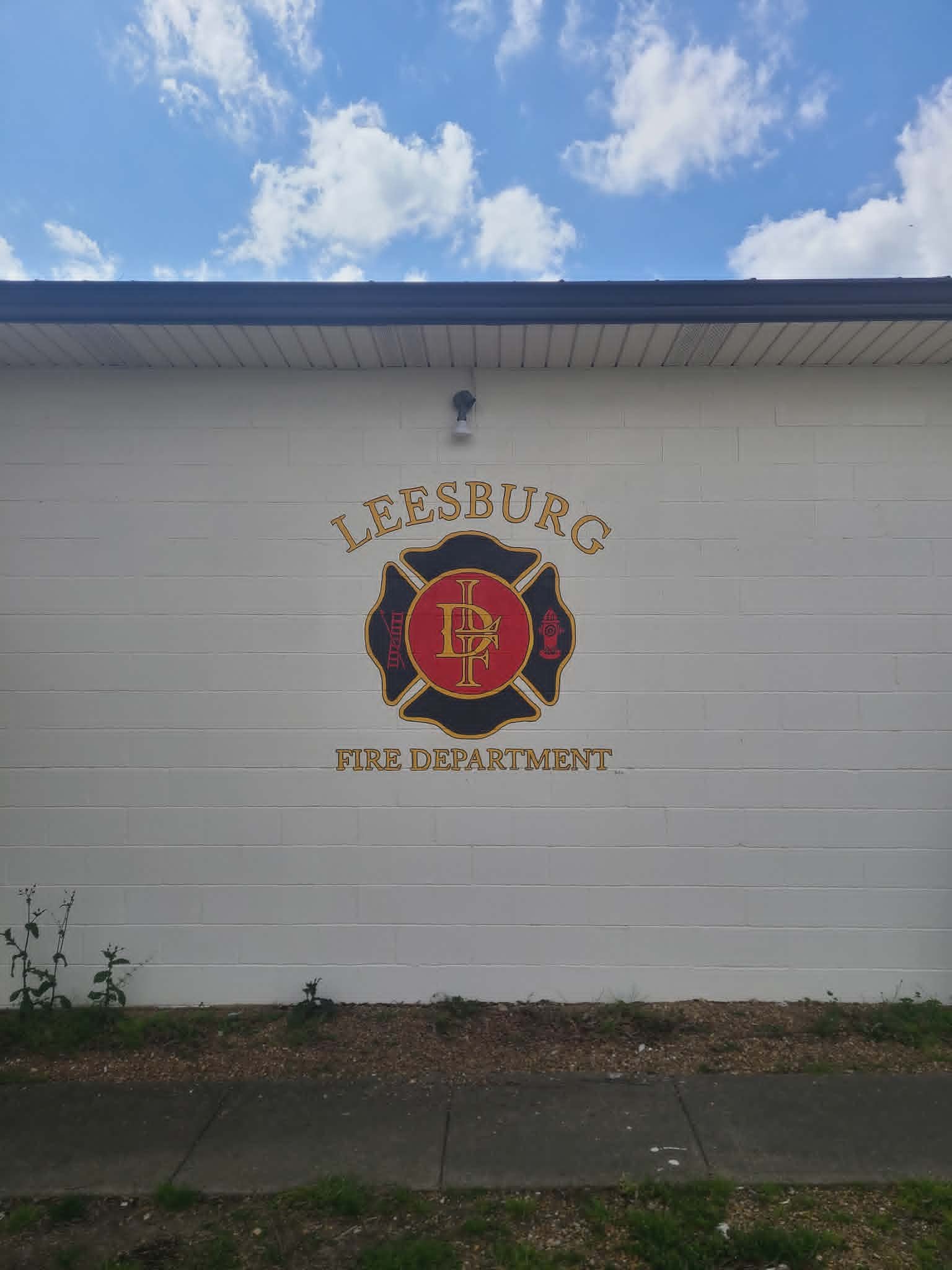 Leesburg Fire Department exterior maltese-cross badge mural in red, gold, and black with classic fire department insignia
