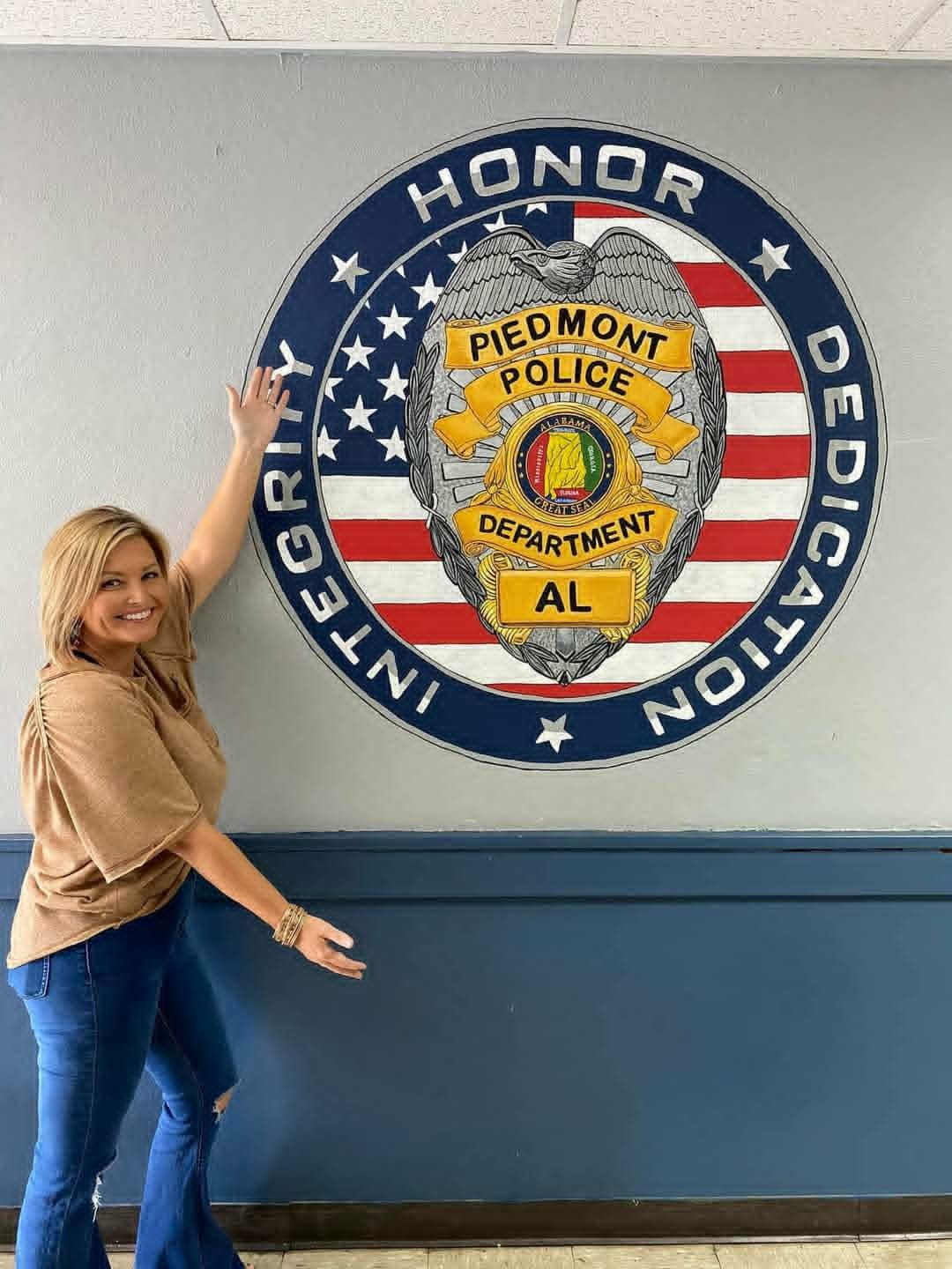 Piedmont Police Department interior mural with a detailed silver and gold badge over an American flag and 'Honor Integrity Dedication' lettering