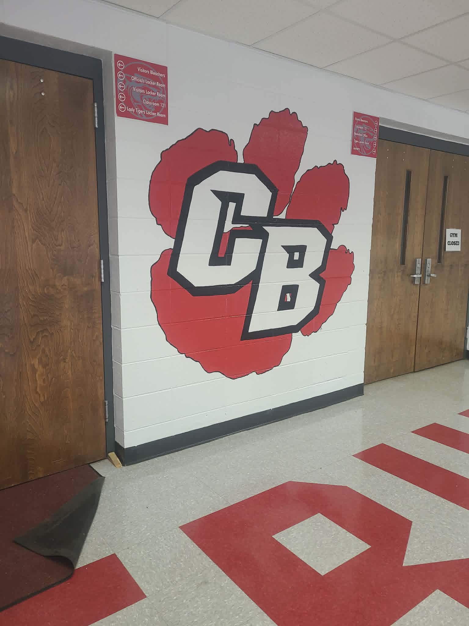 Cedar Bluff Tigers school hallway mural featuring a large red paw print with bold black-outlined 'CB' varsity logo, painted between the gym entrance doors
