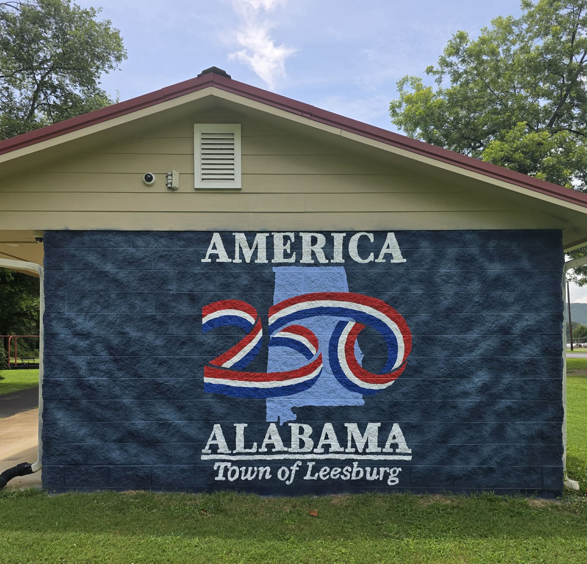 America 250 Alabama mural for the Town of Leesburg, featuring the Alabama state outline and a red, white, and blue 250 ribbon emblem on a dark blue cinderblock wall