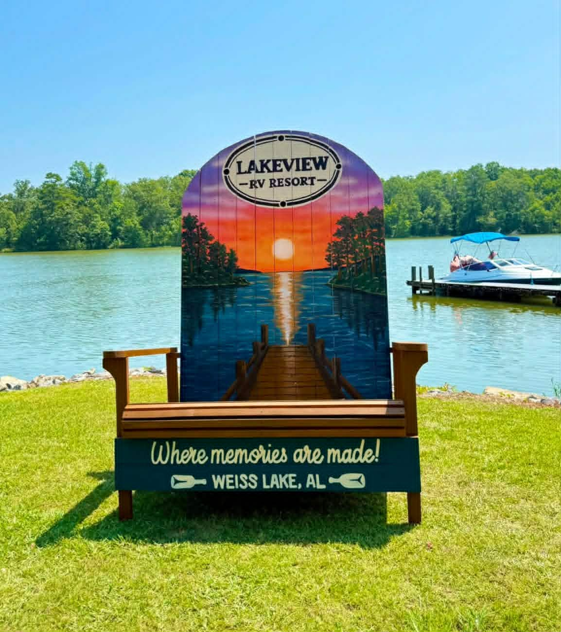 Giant Adirondack-chair photo op for Lakeview RV Resort at Weiss Lake, AL, painted with a lake sunset and dock scene and the words 'Where memories are made'