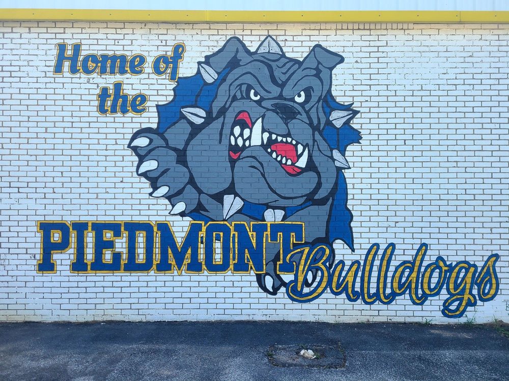 Home of the Piedmont Bulldogs mural with a fierce bulldog mascot bursting through a brick wall