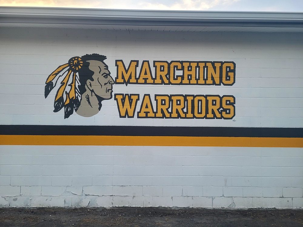 Marching Warriors mural with a warrior chief silhouette in gold and black school colors