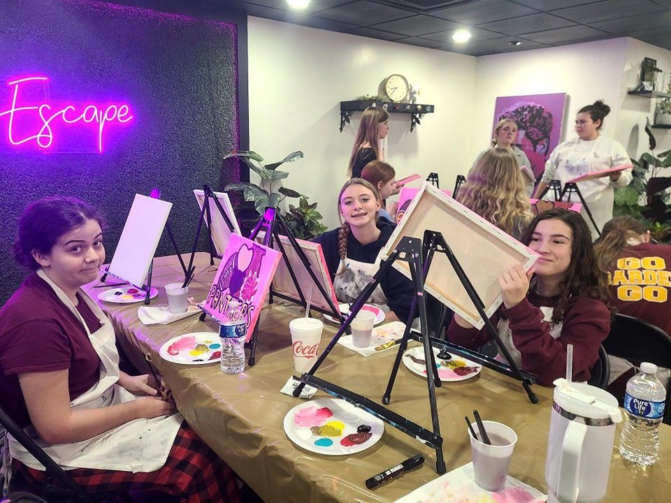 Teen girls painting at a long table party in the My Sweet Escape studio