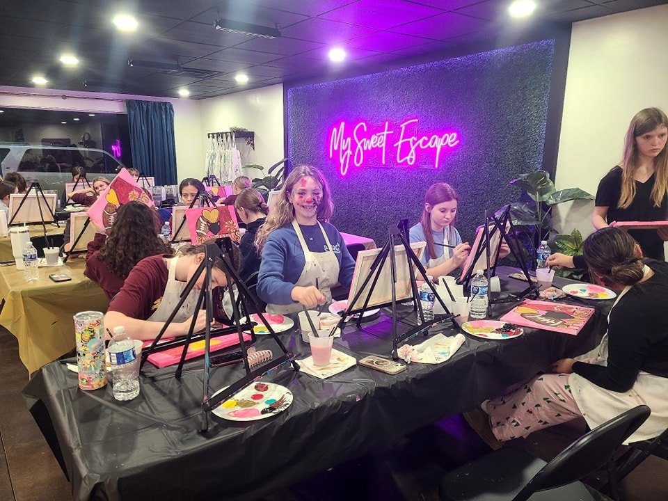 Group of girls painting at a long table at a private paint party in the My Sweet Escape studio