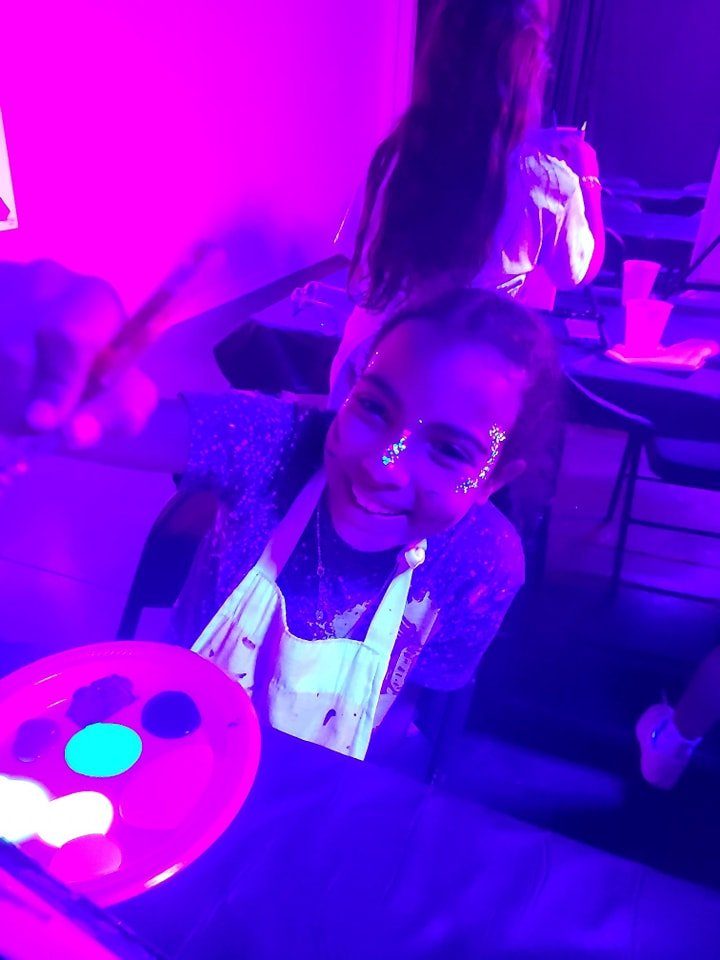 Smiling girl with sparkly glitter face paint at a blacklight paint party