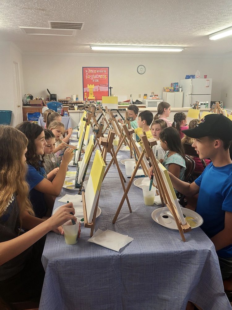 Large group of kids painting together at a church paint party event
