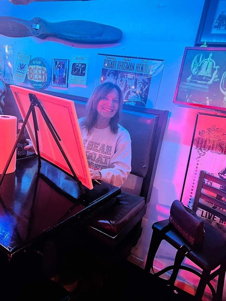 Woman smiling while painting at a private paint party hosted at a local bar