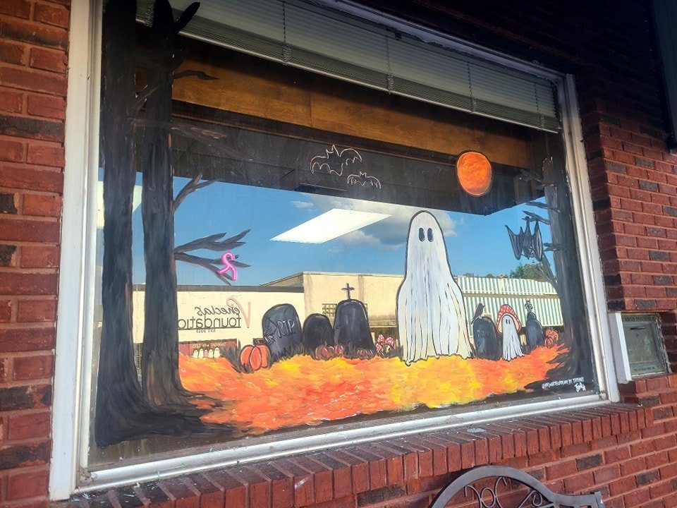 Halloween window painting with a friendly ghost in a graveyard scene