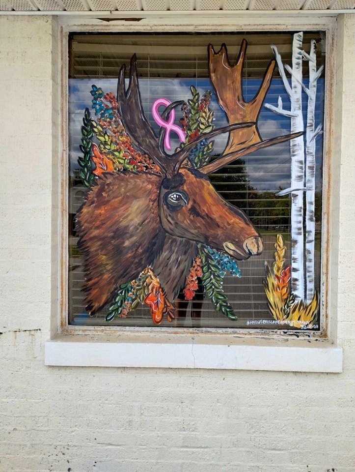 Detailed moose window painting with a pink breast cancer awareness ribbon and autumn foliage