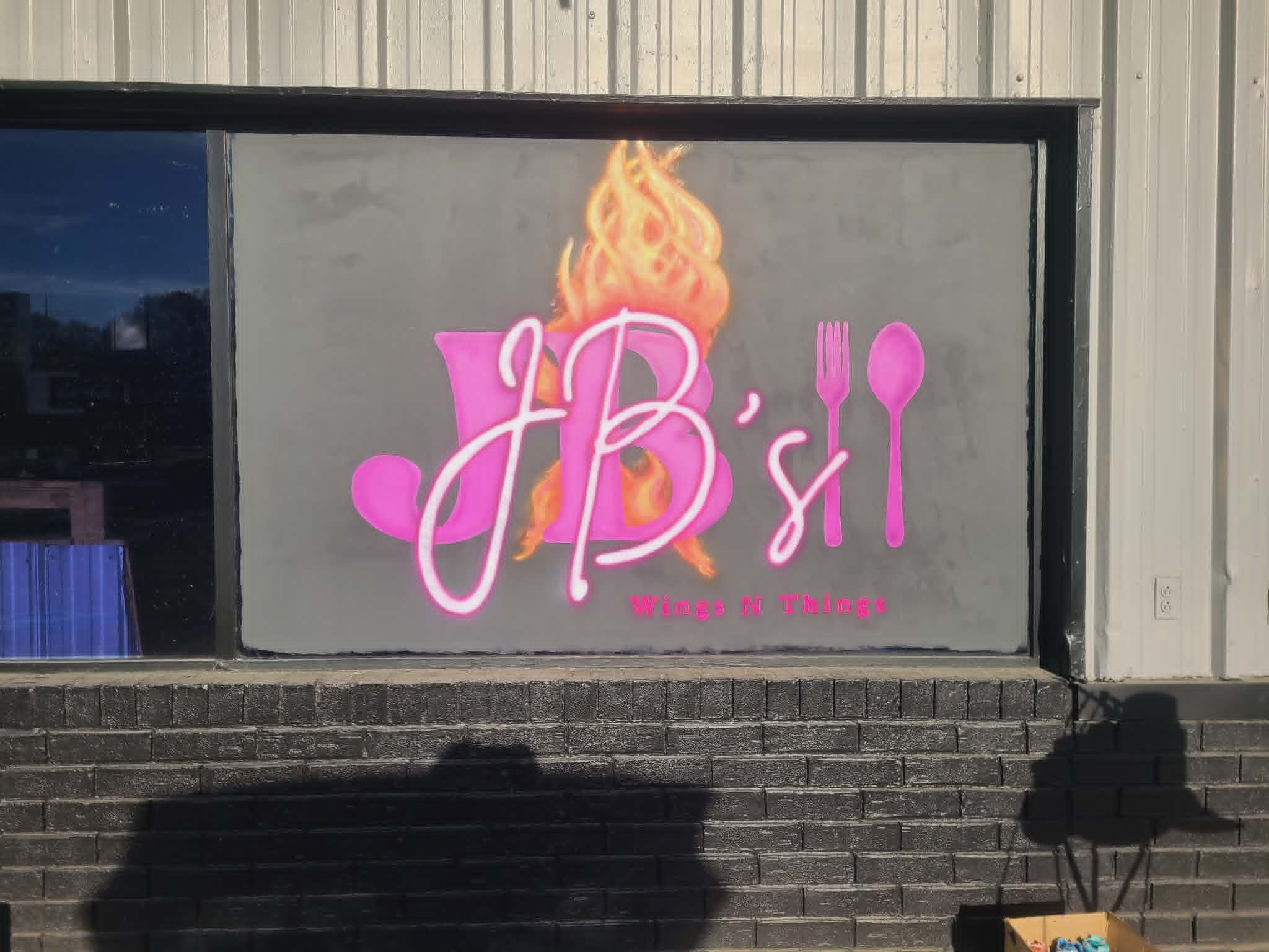 JB's Wings N Things storefront window painting with bold pink airbrushed script lettering, fiery flames, and a pink fork and spoon